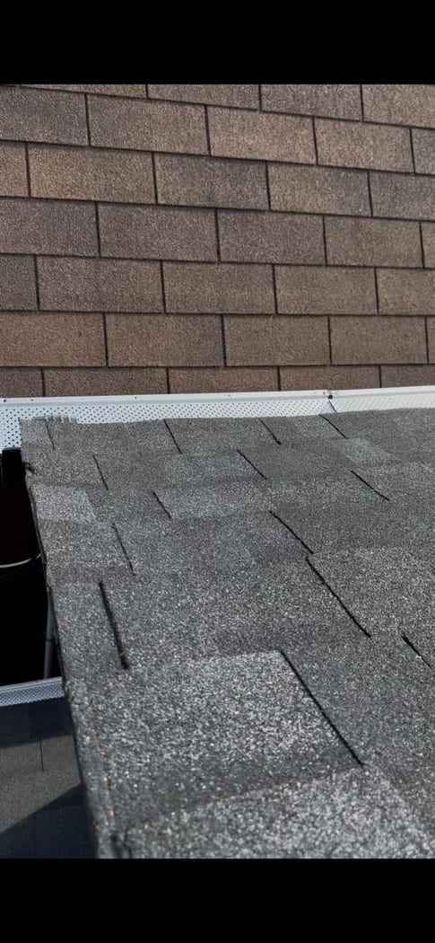 Leaf guard installed along a shingled roof edge